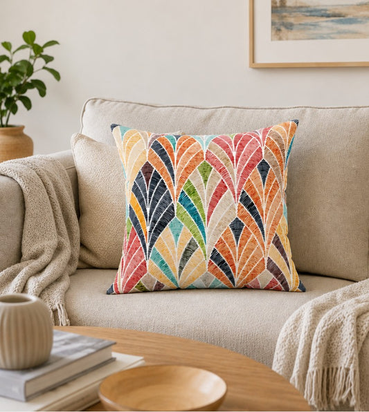 Square throw pillow with colorful leaf fan pattern, stitched edges, beige back on sofa