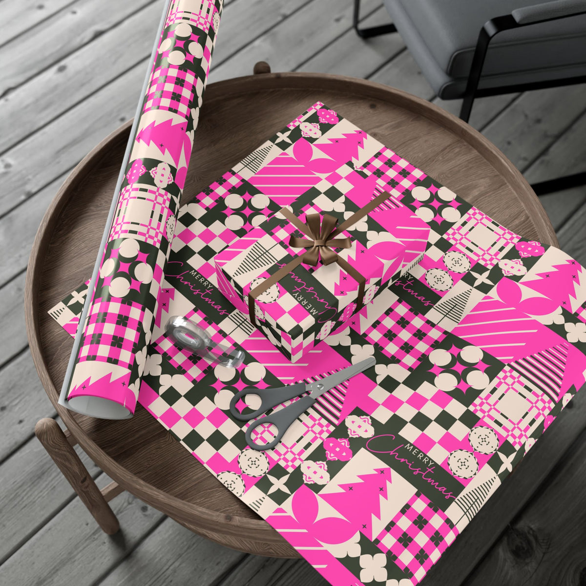 Pink Christmas gift wrap roll with plaid patchwork, bows, stars, and ornaments in black and cream