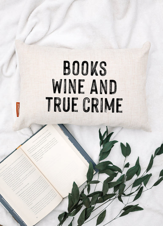 Off-white book-themed pillow with 'BOOKS WINE AND TRUE CRIME' lettering