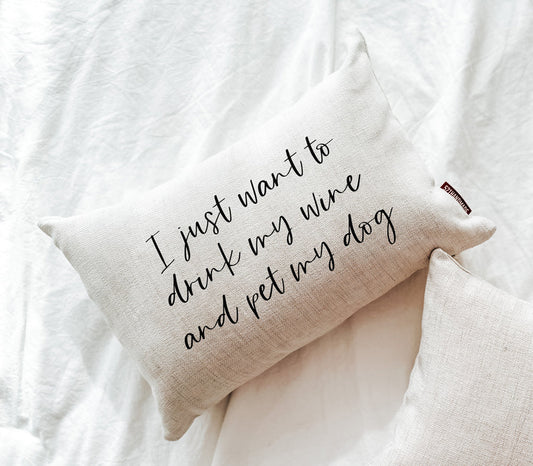 Beige linen-look pillow with quote: “I just want to drink my wine and pet my dog”