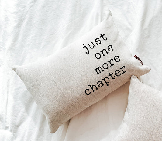 Cream fabric book pillow with black “just one more chapter” text, folded corner detail