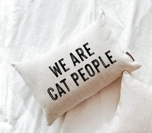 Beige fabric decorative pillow with "WE ARE CAT PEOPLE" text and stitched edging